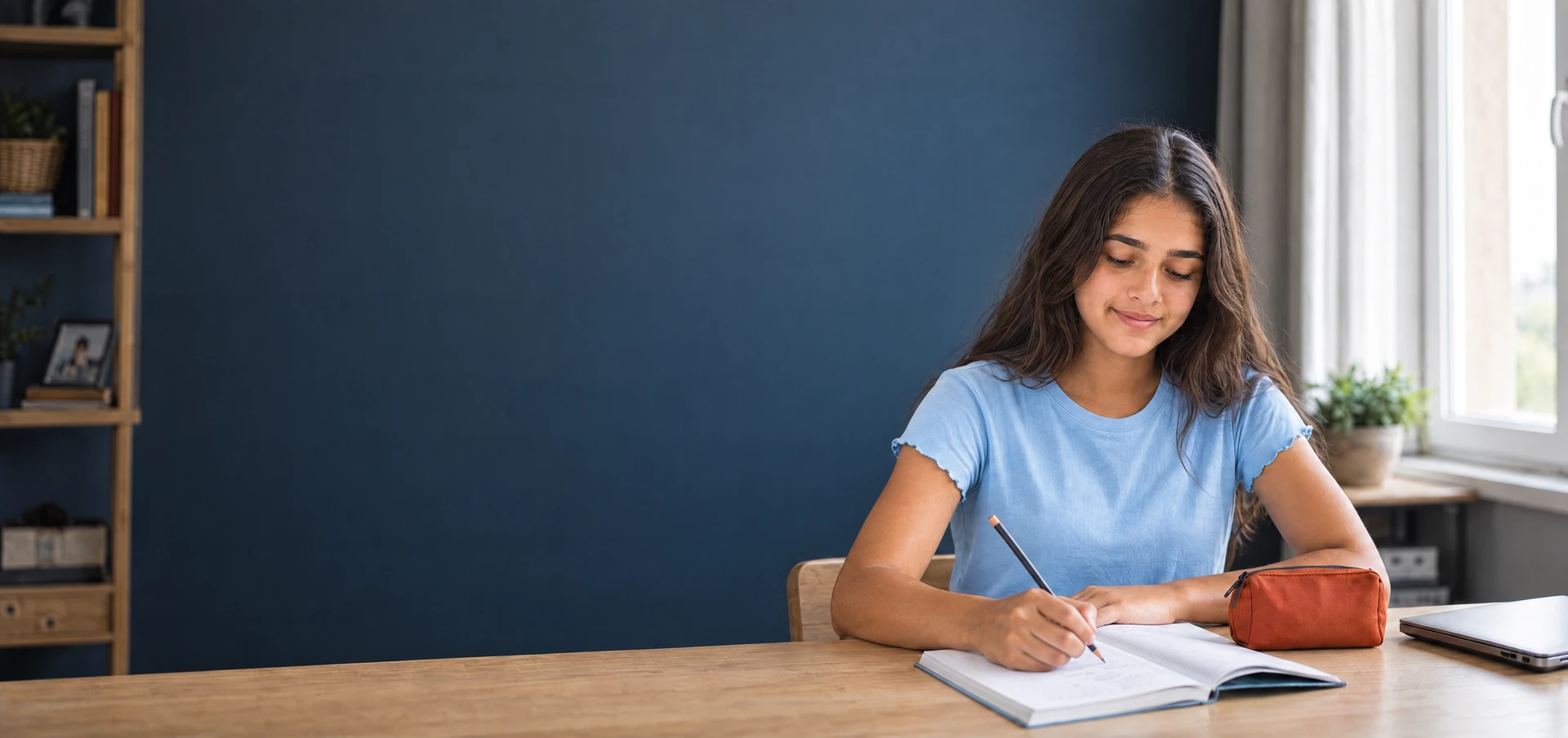 A student working in her notebook beside a sunlit window.